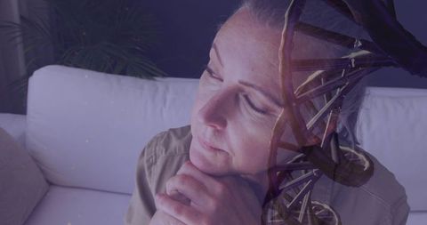 Contemplative mature woman resting on sofa with dna spiral double exposure