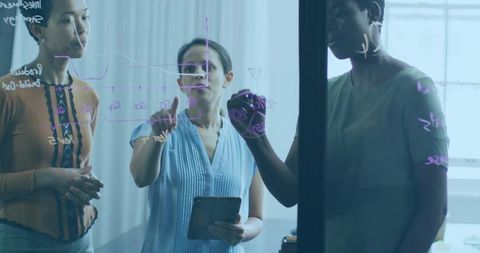 Diverse team of women collaborating on glass board for innovation