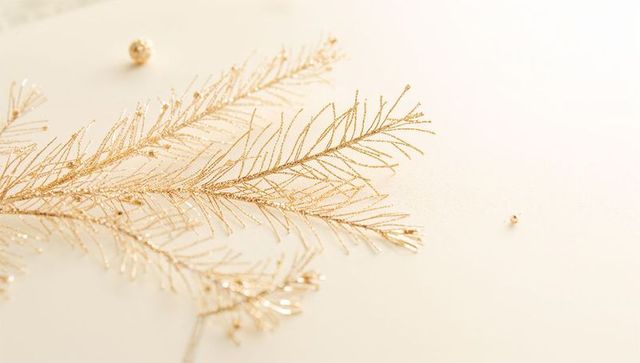 Glittering Gold Branch Resting on Cream Surface Minimalist Holiday Flatlay with Beads