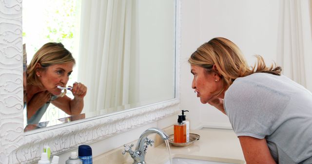 Woman Brushing Teeth in Bathroom Looking into Mirror - Download Free Stock Images Pikwizard.com