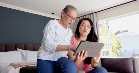 Senior Mother and Daughter Connecting with Tablet in Cozy Bedroom