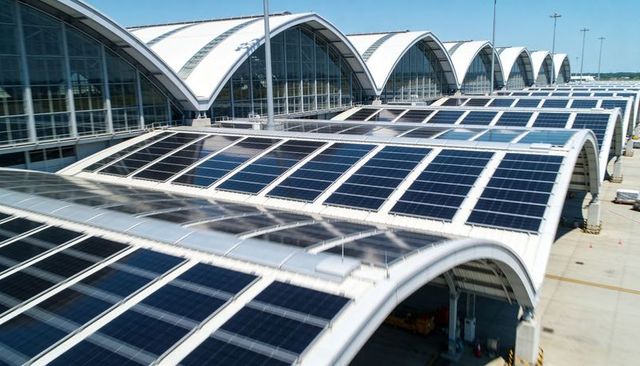 Solar panels on arched airport terminal roofs with vaulted glass facades and apron