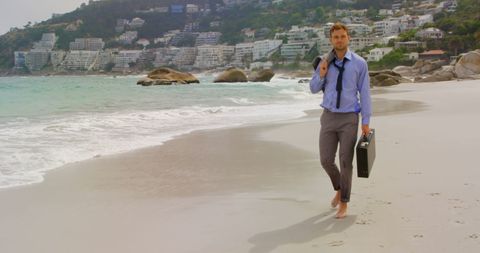 Businessman walking on beach holding briefcase, serenity in contrast
