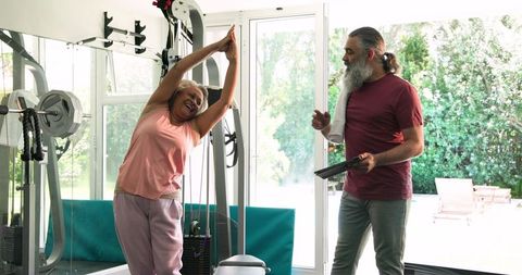 Senior Woman Stretching with Coach in Home Gym Setting