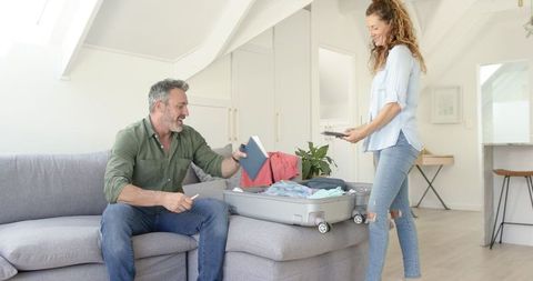 Happy Couple Packing Suitcase at Home for Vacation