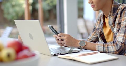 Asian Man Engaging with Digital Devices at Home Office