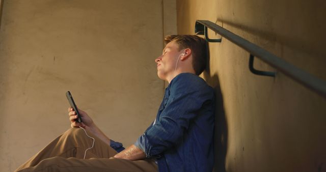 Young Man Relaxing on Stairs Listening to Music - Download Free Stock Images Pikwizard.com