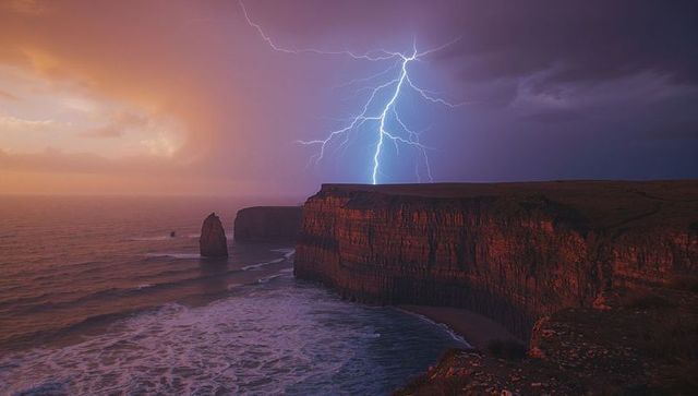 Lightning Bolt Striking Sea Cliff at Twilight with Stormy Seas