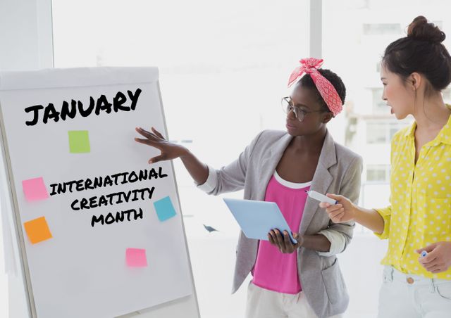 Digital composite of businesswomen discussing over international creativity month text on flipchart. creative business and planning.