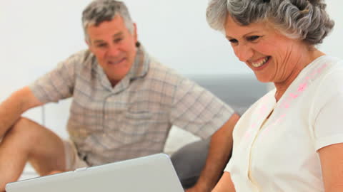 Senior Couple Enjoying Laughter While Using Laptop Together