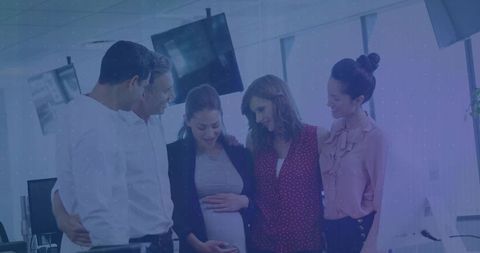 Colleagues celebrating pregnant coworker in modern office