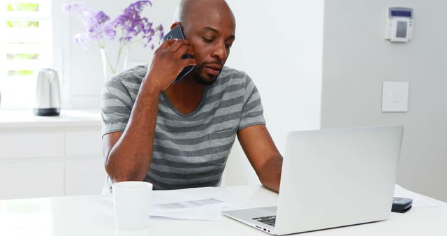 Young Man Multitasking at Home Office with Laptop and Phone - Download Free Stock Images Pikwizard.com