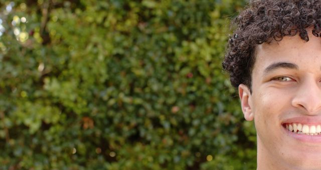 Young Man Smiling with Curly Hair in Sunny Garden - Download Free Stock Images Pikwizard.com