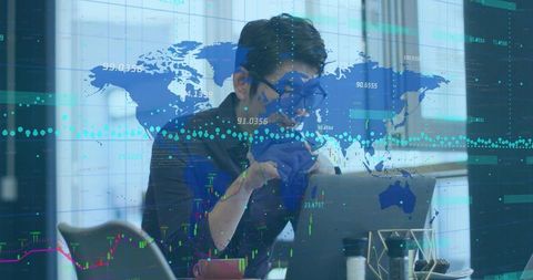 Asian professional analyzing global financial charts on laptop with digital map overlay
