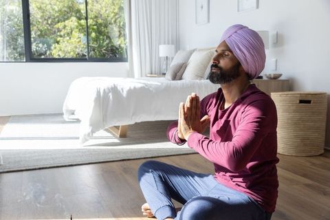 Mid Adult Man Meditating in Sunlit Bedroom for Wellness and Peace