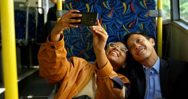 Diverse couple sitting in city bus taking selfie with smartphone. Communication, transport, city living and lifestyle, unaltered.