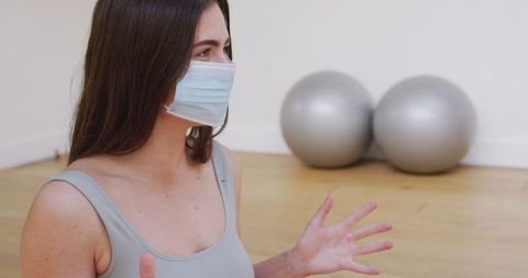 Yoga instructor in mask teaching virtual class during pandemic