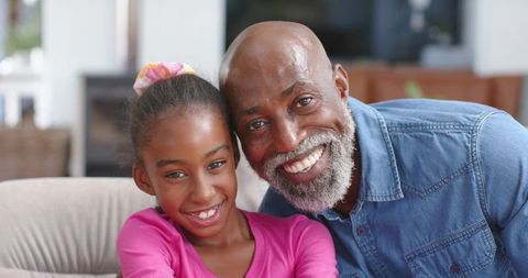 African american father and daughter smiling on sofa in cozy living room, family warmth