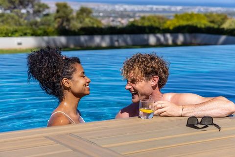 Couple enjoying lemon drink at infinity pool overlooking cityscape on luxury terrace