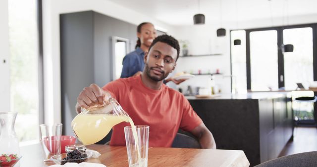 Man Pouring Juice While Woman Prepares Food in Modern Kitchen - Download Free Stock Images Pikwizard.com