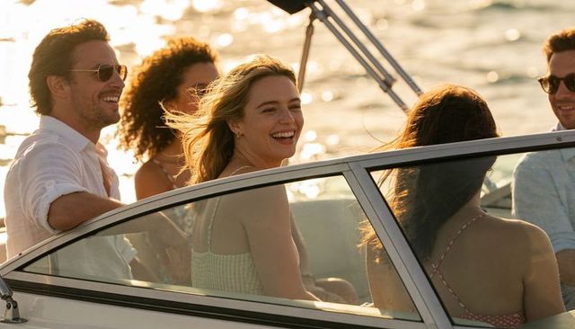 Laughing friends cruising on boat at golden hour, smiling blonde in sundress enjoying summer