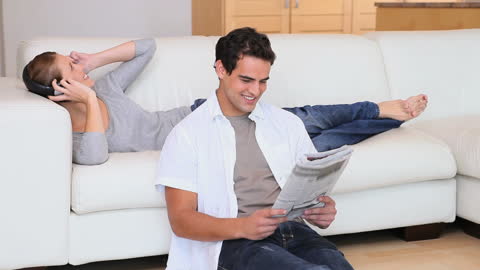 Couple Relaxing at Home with Music and Newspaper