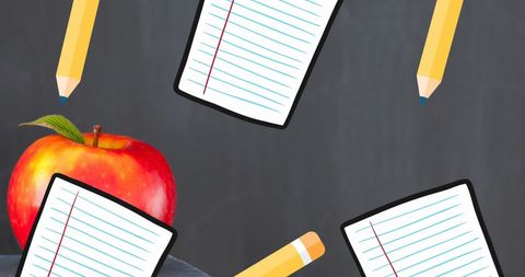 School essentials with apple and paper on blackboard