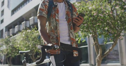 Casual Cyclist Checking Smartphone on Urban Sidewalk