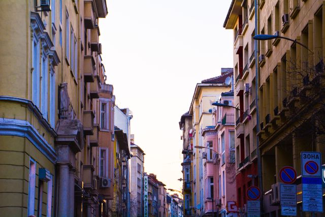 Narrow street lined with colorful historic buildings and facades at dusk. Ideal for use in projects related to urban exploration, city travel guides, historic architecture, and European cityscapes.