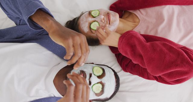 Couple lying down enjoying spa day with face masks and cucumber slices over eyes. Perfect for promoting skincare products, relaxation techniques, wellness routines, or lifestyle blogs that focus on self-care and pampering experiences.