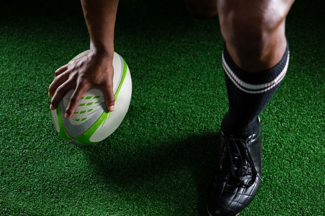 High angle view sportsman kicking rugby ball while standing on field