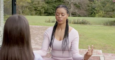 Diverse women meditating on brick patio in pink loungewear practicing mindfulness outdoors