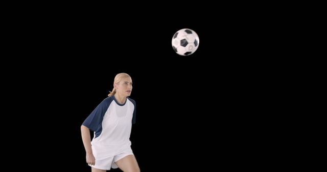 Woman in white and navy soccer uniform focusing on an incoming soccer ball. Dynamic capture of sports action, perfect for illustrating sports techniques, training guides, and team promotions. Isolated black background allows for easy image integration.