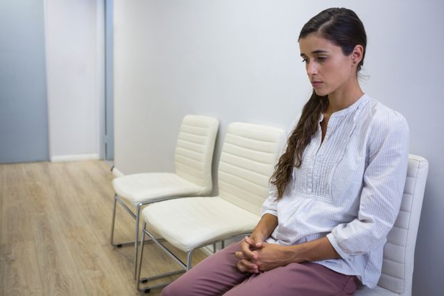 Sad patient sitting on chair in waiting room at hospital