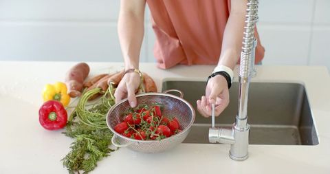 Washing vine tomatoes under modern spring faucet in bright minimalist kitchen