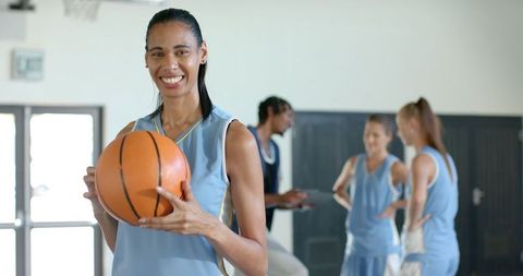 Female basketball players receiving coaching session in gym