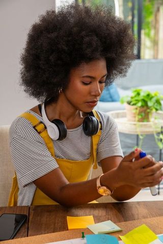 Creative woman working at home with headphones and sticky notes