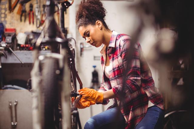 Focused Female Mechanic Repairing Bicycle in Workshop - Download Free Stock Images Pikwizard.com