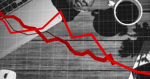 Red declining graph overlay on wooden office desk