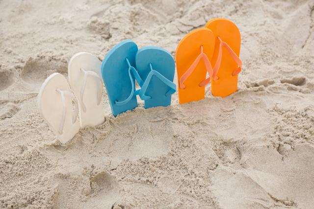 Multi-color flip flops arranged in a row in sand at beach