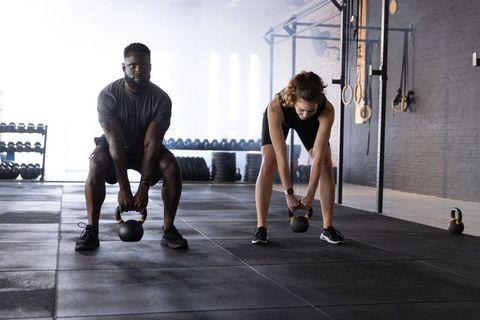 Pair lifting kettlebells in industrial gym, partner strength training, focused workout