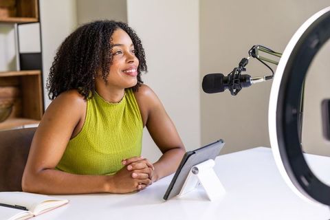 African american woman hosting podcast in home studio with microphone and ring light