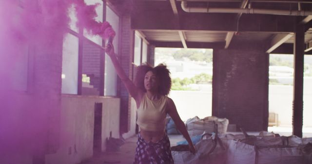 Young woman with colored smoke bomb in urban warehouse - Download Free Stock Images Pikwizard.com