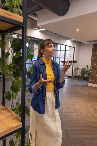 Woman Using Smartphone for Voice Commands in Modern Office Space