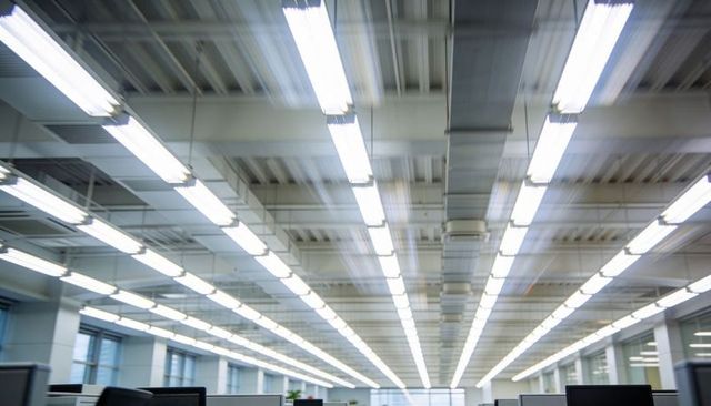 Converging fluorescent lights creating motion blur in modern open-plan office interior