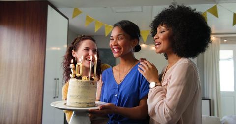 Multiracial friends celebrating a 30th birthday with cake and candles