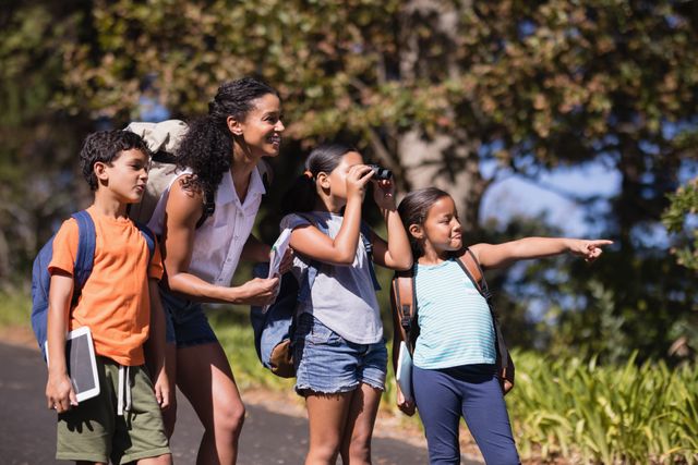 Girl pointing away with friends and teacher on street during summer field trip