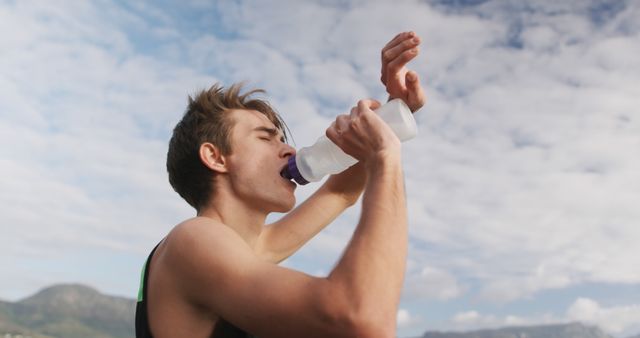 Athlete Hydrating Outdoors with Water Bottle Against Blue Sky - Download Free Stock Images Pikwizard.com