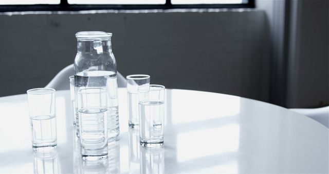 Glass Jug with Water and Drinking Glasses on Round White Table in Minimalist Setting - Download Free Stock Images Pikwizard.com