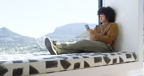 Relaxed young man browsing on smartphone overlooking urban view